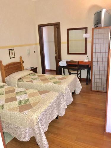 a room with three beds and a table and a mirror at B&B La Vela in Rieti