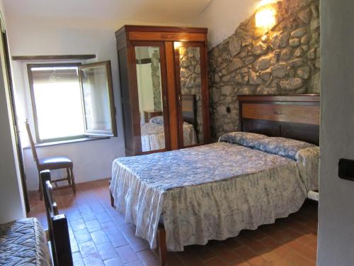 een slaapkamer met een bed en een stenen muur bij Mas el Llach in La Vall de Bianya