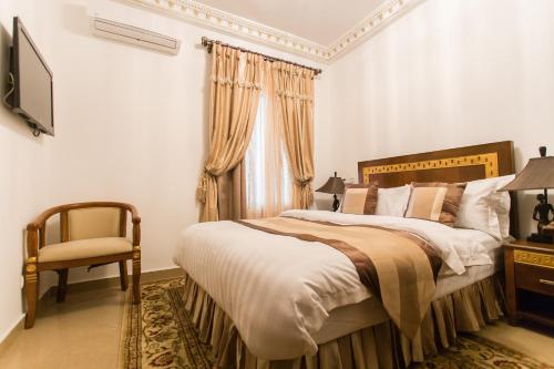 a bedroom with a large bed and a chair at Résidence Hôtelière Le Jomonia in Libreville