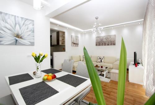 a white living room with a white table and green plants at Apartment Joy in Belgrade