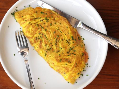 an omelet on a white plate with a fork and knife at East End Retreat in New Delhi