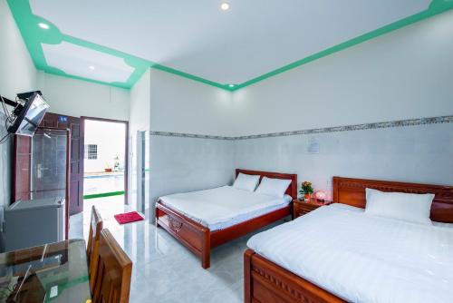 sypialnia z 2 łóżkami i telewizorem w obiekcie Hotel Nguyên Toàn w Duong Dong
