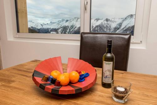 a plate of fruit on a table with a bottle of wine at Chalet la cordée in Bettmeralp