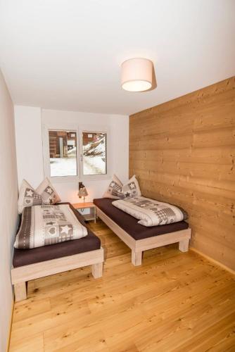 two beds in a room with wooden floors at Chalet la cordée in Bettmeralp