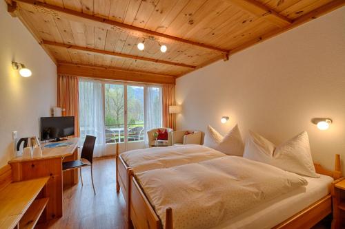 a bedroom with a bed and a desk and a television at Neuhaus Golf- & Strandhotel in Interlaken