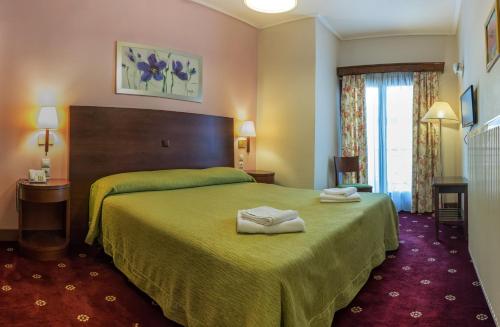 a hotel room with a green bed with two towels on it at City Hotel Apollonion in Karpenision