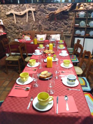 a table with a red table cloth with food and drinks at Antigua Posada, Valle del Jerte in Tornavacas