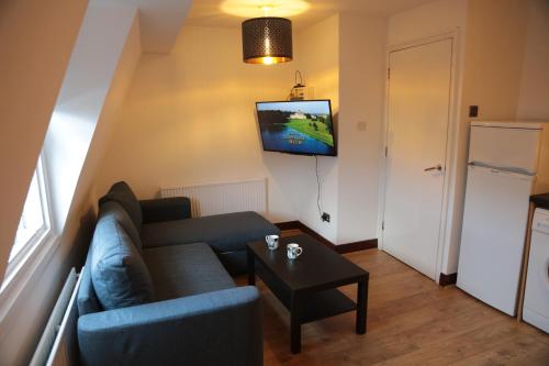 uma sala de estar com um sofá e uma televisão na parede em Kings Cross Apartments em Londres