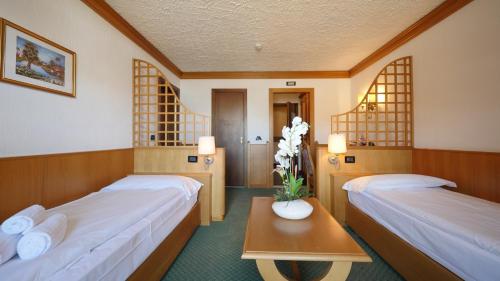 a room with two beds and a table with flowers on it at Hotel Intermonti in Livigno