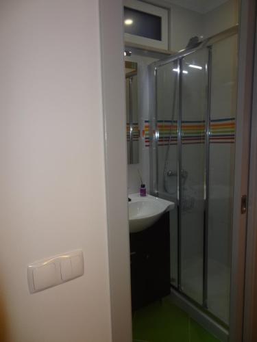 uma casa de banho com uma cabina de duche em vidro e um lavatório. em Fisherman's Palace em Olhão