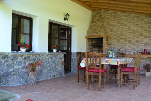 um pátio com uma mesa e cadeiras e uma lareira em El Molin De Frieras em Posada de Llanes