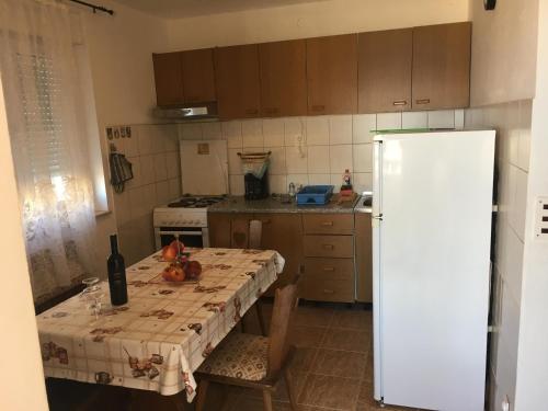 a kitchen with a table and a white refrigerator at Apartments Niko in Stinica