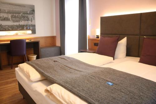 a bedroom with a bed with a blanket on it at Boutique Hotel Beckenlehner in Unterhaching