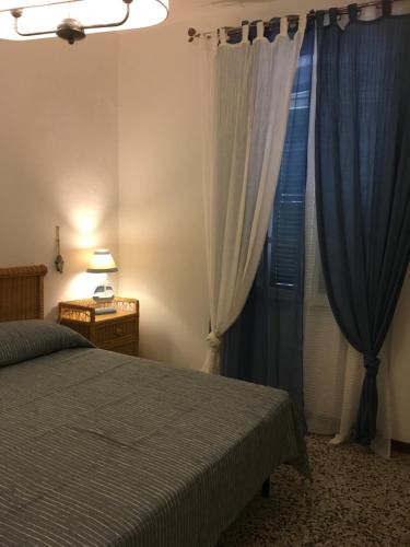 タラモーネにあるCaterina al mareのベッドルーム1室(ベッド1台、青いカーテン付きの窓付)