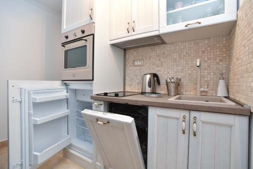 a kitchen with white cabinets and a sink and an open refrigerator at Old Town Skyline apartment 3 in Budva