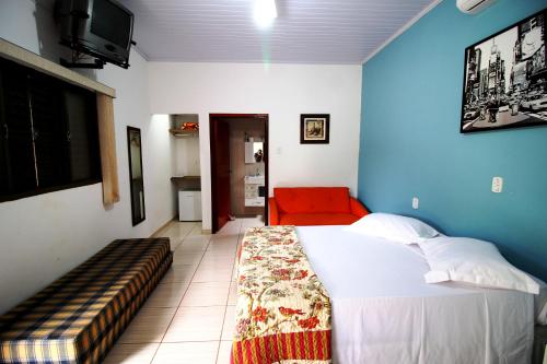 una camera da letto con un letto e un divano rosso di Pousada Akonxego a Olímpia