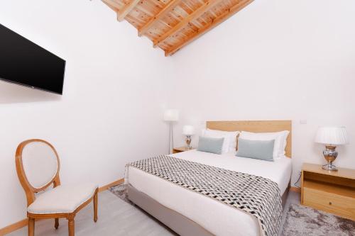 a bedroom with a bed and a tv and a chair at Pico Dreams in São Roque do Pico