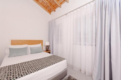 a white bedroom with a bed and white curtains at Pico Dreams in São Roque do Pico