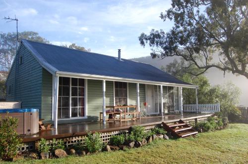 a green house with a porch and a deck at Cadair Cottages in Rosebrook