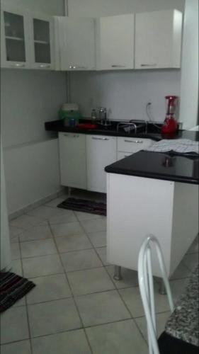 a kitchen with white cabinets and a black counter top at Apartamento confortável in Goiânia