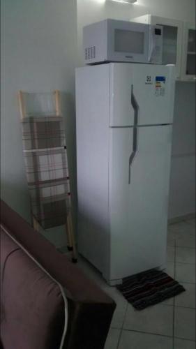a white refrigerator with a microwave on top of it at Apartamento confortável in Goiânia