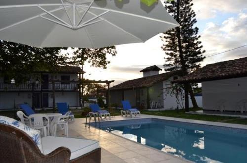 - une piscine avec des chaises et un parasol à côté d'une maison dans l'établissement Pousada Maria Farinha, à Búzios