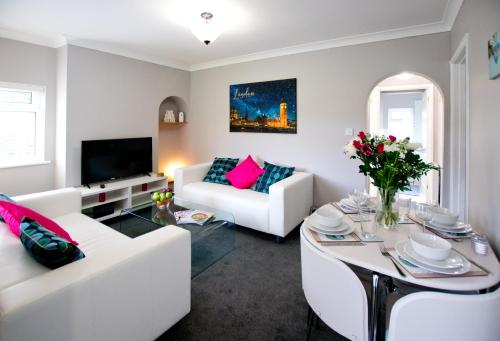 a living room with two white couches and a tv at Grove Cottage in Basingstoke