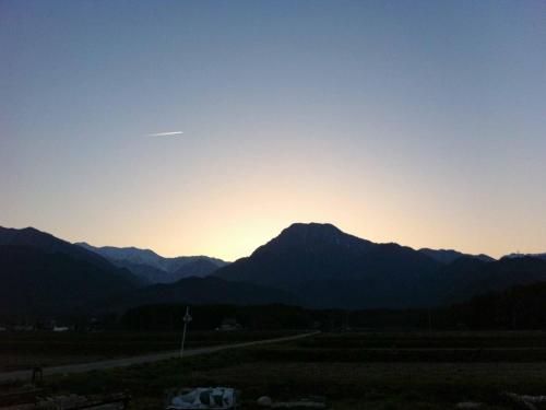 a sunset over a mountain range with a road at Canadian Loghouse Inn AzuminoYujin in Azumino