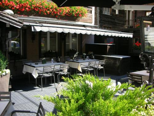 an outdoor patio with tables and chairs and flowers at Roby in Saas-Grund