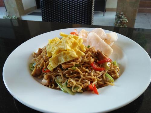 a plate of food with noodles and chips on a table at The Swaha Ubud Hotel in Sukawati