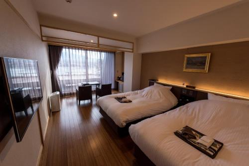 a hotel room with two beds and a desk at Mizno Hotel in Fujikawaguchiko