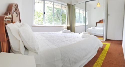 1 dormitorio con 1 cama blanca grande y espejo en Lowest Price Clean Linen free stuff free car parking inside property W1, en Wentworthville