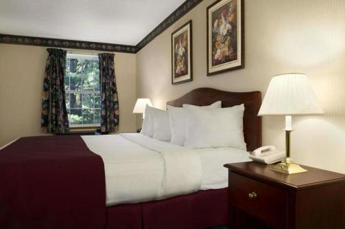 a hotel room with a bed and a phone on a table at Days Inn by Wyndham Grayling in Grayling
