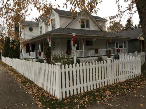 a white picket fence in front of a house with christmas decorations at Finlay House Bed and Breakfast Niagara - on - the - Lake in Niagara on the Lake