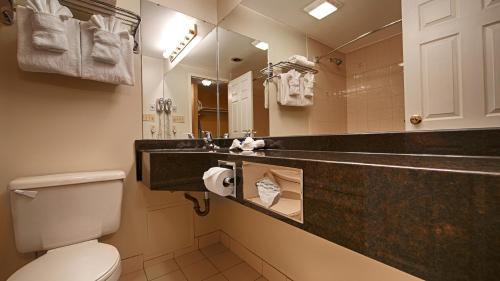 La salle de bains est pourvue d'un lavabo, de toilettes et d'un miroir. dans l'établissement Best Western Colonel Butler Inn, à Niagara on the Lake