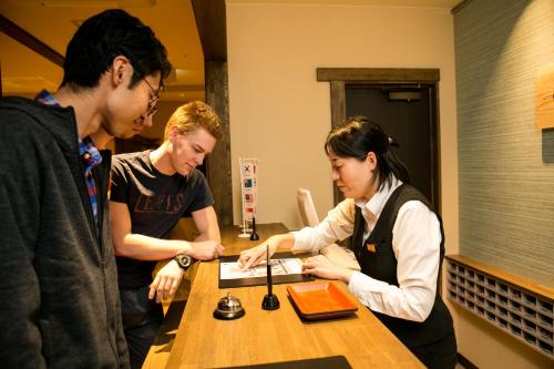 een groep mensen die rond een tafel staan bij Kanazawa Capsule Hotel Musashimachi in Kanazawa