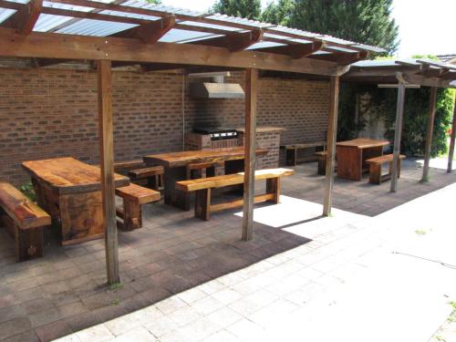 a patio with wooden tables and benches under a pavilion at Big Trout Motel in Oberon
