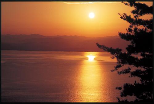 a sunset over the water with the sun in the sky at Kitabiwako Hotel Grazie in Nagahama