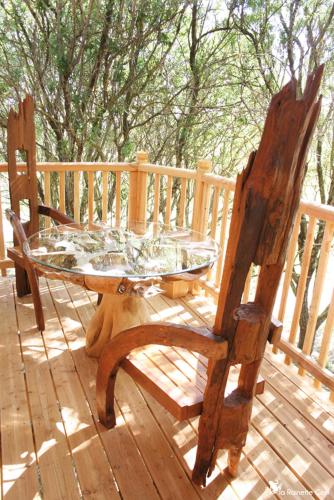 a glass table and two wooden chairs on a deck at Cabane d'Amour in Béziers