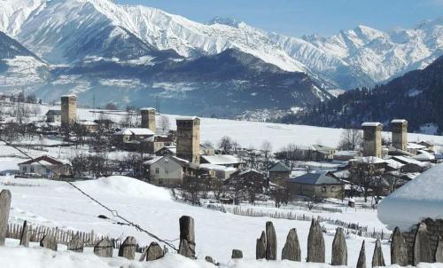 a village covered in snow with mountains in the background at Mestia 4 season in Mestia
