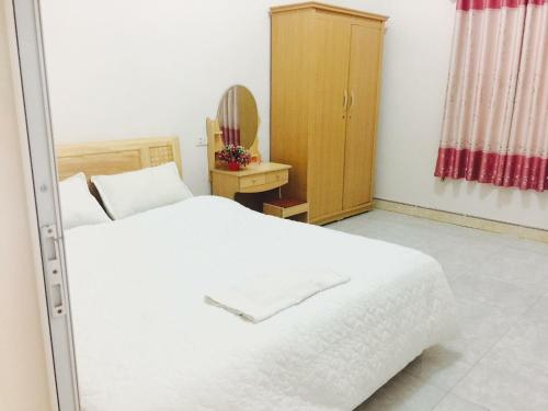 um quarto com uma cama branca e um armário de madeira em Nhà Nghỉ Hạnh Phúc em Mộc Châu