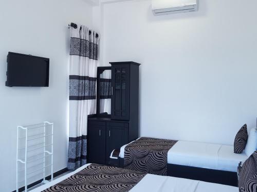 a bedroom with a bed and a dresser and a tv at Trinco Lagoon in Trincomalee