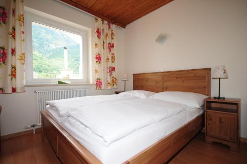 a bedroom with a large white bed with a window at Schlossalm Appartement in Bad Hofgastein