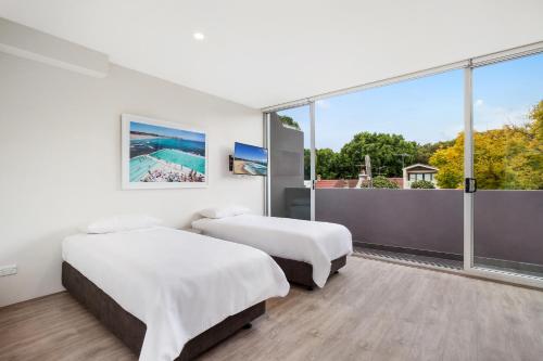 dwa łóżka w pokoju z dużym oknem w obiekcie Bondi Beach Studio King Suite + Balcony w mieście Sydney
