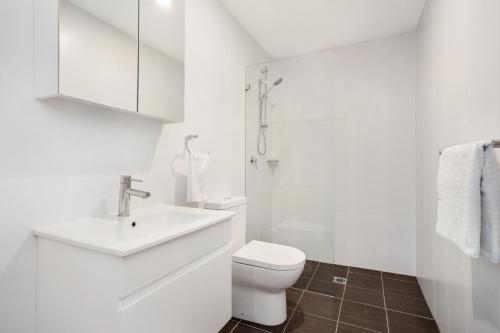 a white bathroom with a toilet and a sink at Bondi Beach Studio King Suite + Balcony in Sydney