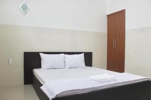 a bed with white sheets and a wooden cabinet at HaiVan HosTel in Chau Doc