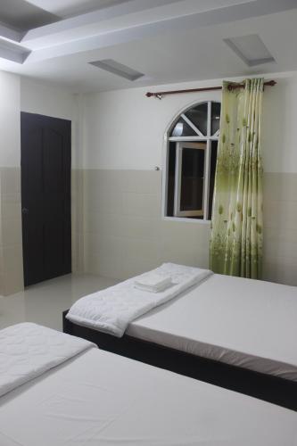 a bedroom with two beds and a window at HaiVan HosTel in Chau Doc