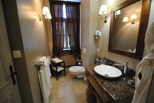 a bathroom with a sink and a toilet and a mirror at Hôtel Restaurant Spa Le Sauvage in Besançon