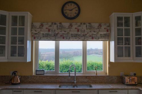 uma janela de cozinha com um relógio por cima de um lavatório em The Doc's self catering em Greencastle