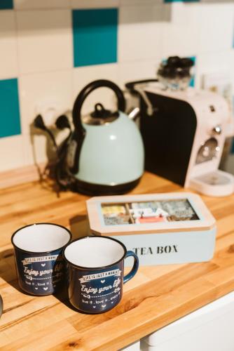 two coffee cups and a tea kettle on a counter at MOOKI Beach Apartment in Bodensdorf
